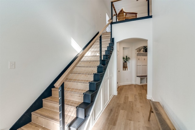 stairs featuring wood-type flooring and a high ceiling