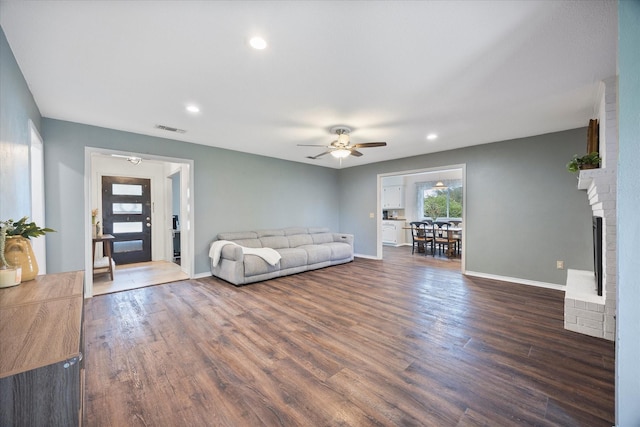 unfurnished living room featuring a fireplace, dark hardwood / wood-style floors, and ceiling fan