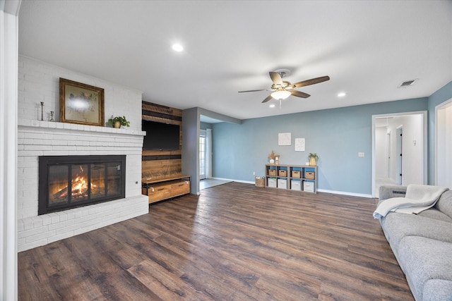 living room with a brick fireplace, dark hardwood / wood-style floors, and ceiling fan