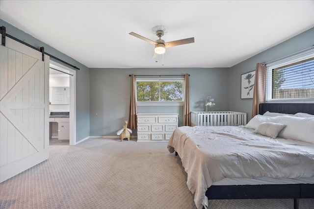 bedroom with light colored carpet, connected bathroom, a barn door, and multiple windows