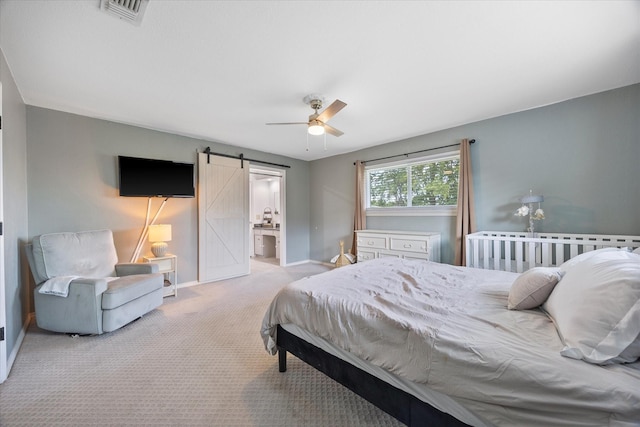 carpeted bedroom featuring ceiling fan, ensuite bath, and a barn door