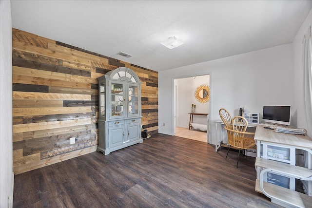 office space featuring wooden walls, dark hardwood / wood-style flooring, and a textured ceiling