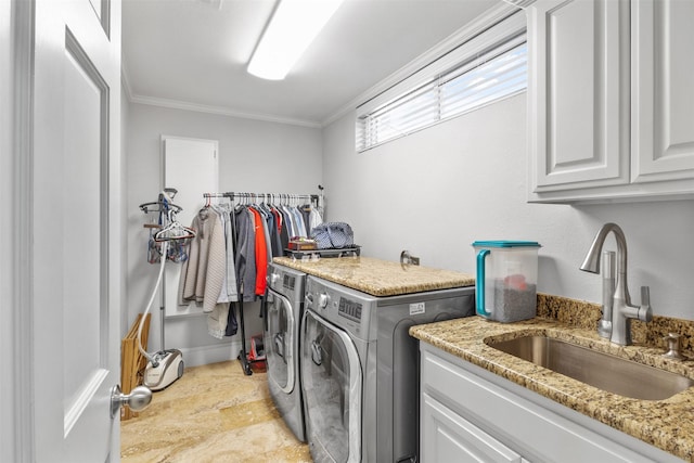 washroom featuring washing machine and clothes dryer, sink, cabinets, and ornamental molding