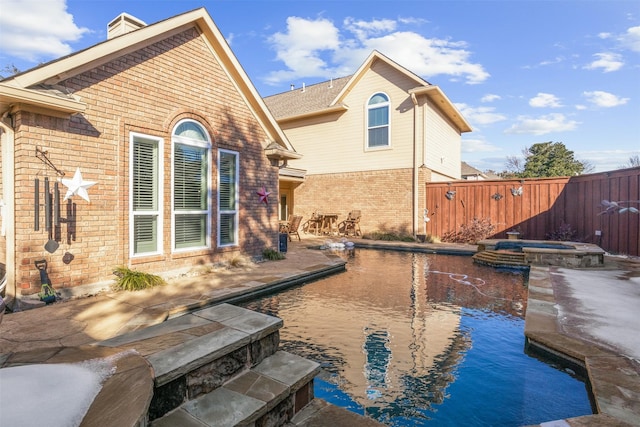 rear view of property featuring a swimming pool with hot tub and a patio