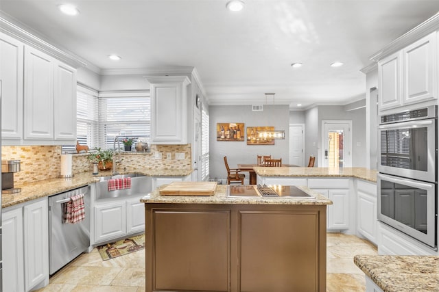 kitchen with white cabinets, appliances with stainless steel finishes, a center island, and sink