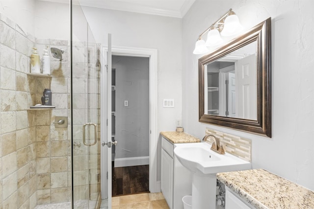 bathroom with sink, a shower with shower door, and crown molding