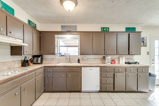 kitchen with sink, light tile patterned floors, a textured ceiling, and white appliances