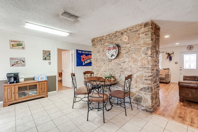 tiled dining space with a textured ceiling