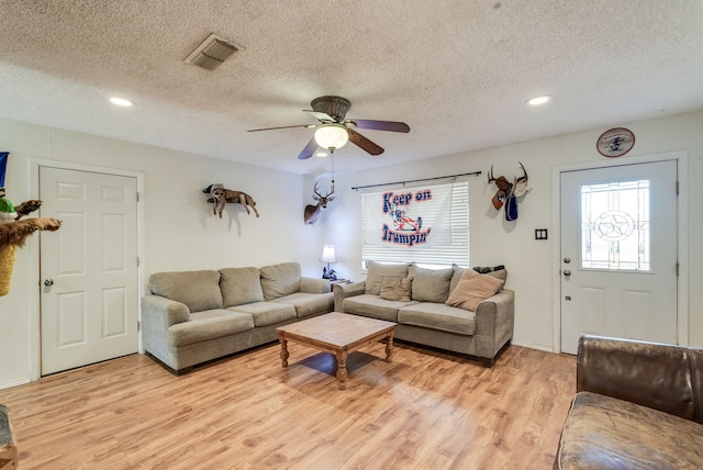 living room featuring ceiling fan, a textured ceiling, and light hardwood / wood-style flooring