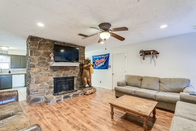 living room with sink, wood-type flooring, a textured ceiling, ceiling fan, and a fireplace