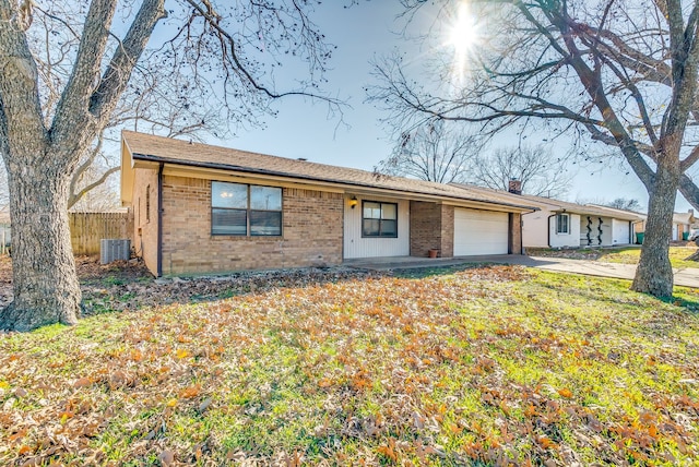 ranch-style house with a garage, central AC unit, and a front lawn