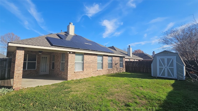 back of property featuring solar panels, a yard, a shed, and a patio area