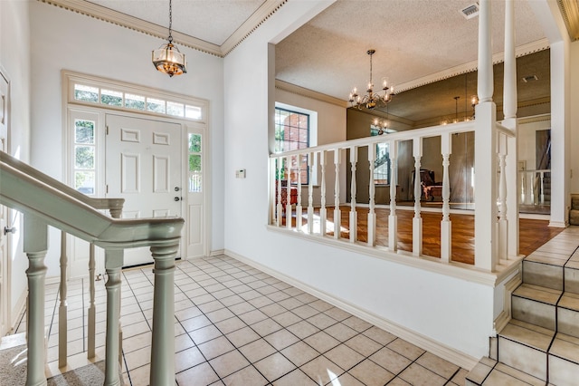 entryway with tile patterned flooring, crown molding, a textured ceiling, and a chandelier