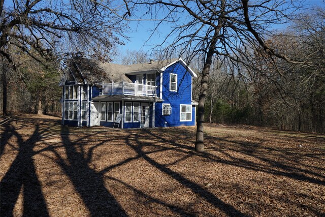 rear view of property featuring a balcony and a sunroom