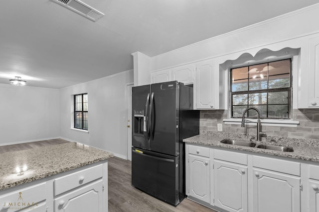 kitchen featuring white cabinetry, black fridge with ice dispenser, sink, and tasteful backsplash