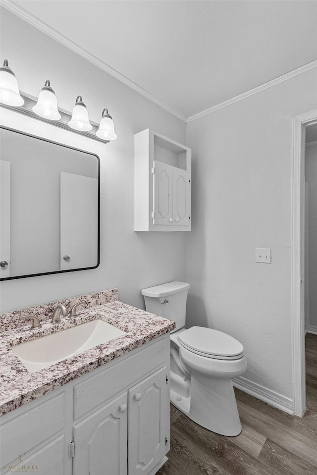 bathroom featuring wood-type flooring, vanity, crown molding, and toilet