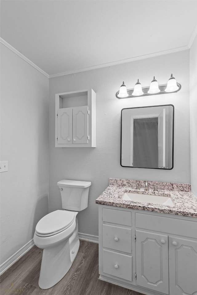 bathroom with hardwood / wood-style flooring, ornamental molding, vanity, and toilet