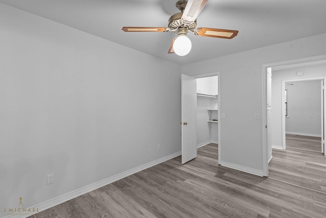 unfurnished bedroom featuring a spacious closet, light hardwood / wood-style floors, a closet, and ceiling fan