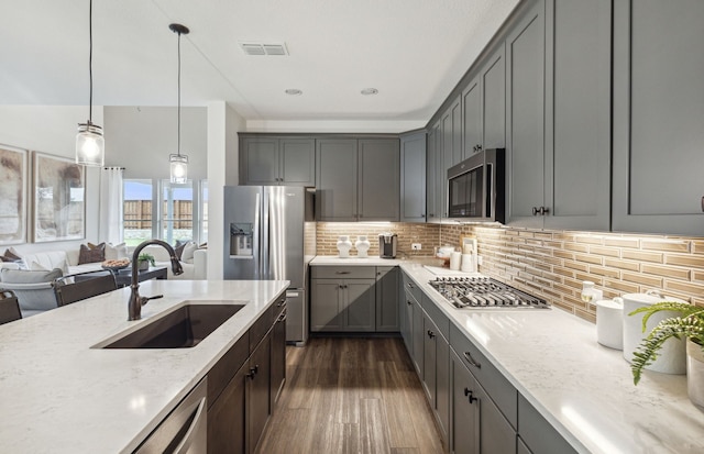 kitchen featuring sink, appliances with stainless steel finishes, gray cabinetry, light stone counters, and decorative light fixtures