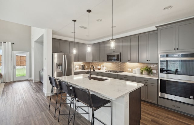 kitchen with appliances with stainless steel finishes, decorative light fixtures, sink, a breakfast bar area, and light stone counters