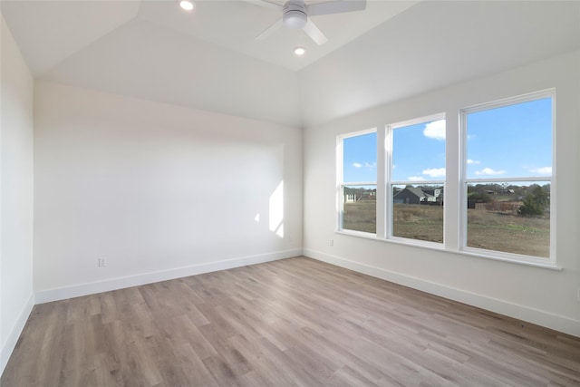 spare room featuring ceiling fan, lofted ceiling, and light wood-type flooring