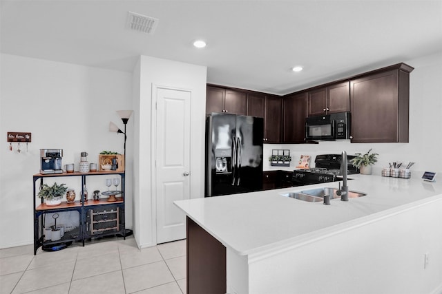 kitchen featuring dark brown cabinetry, sink, kitchen peninsula, light tile patterned floors, and black appliances