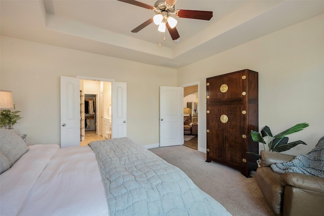 bedroom with a raised ceiling, ceiling fan, and light colored carpet