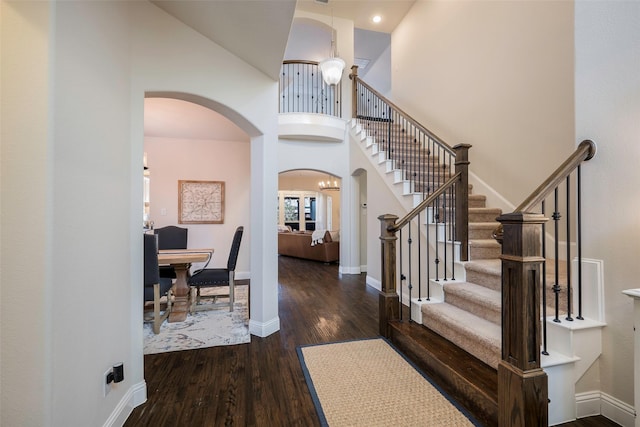 foyer with a high ceiling, dark hardwood / wood-style floors, and an inviting chandelier