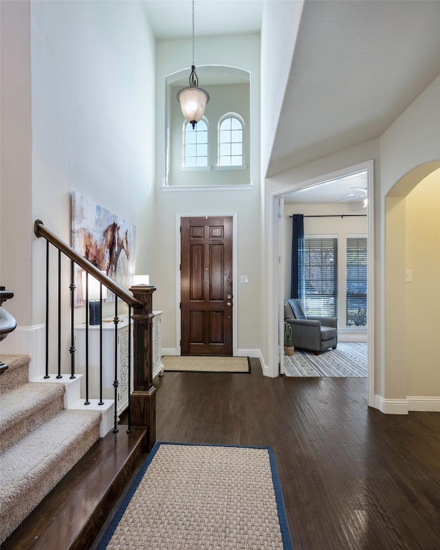 foyer featuring a towering ceiling and dark wood-type flooring