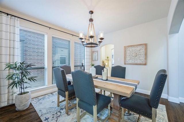 dining area featuring dark wood-type flooring and a notable chandelier