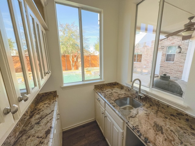 kitchen featuring dark hardwood / wood-style floors, sink, white cabinets, ceiling fan, and light stone countertops