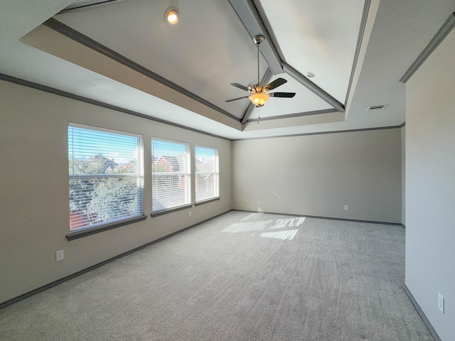 unfurnished room featuring vaulted ceiling, ornamental molding, light colored carpet, ceiling fan, and a tray ceiling