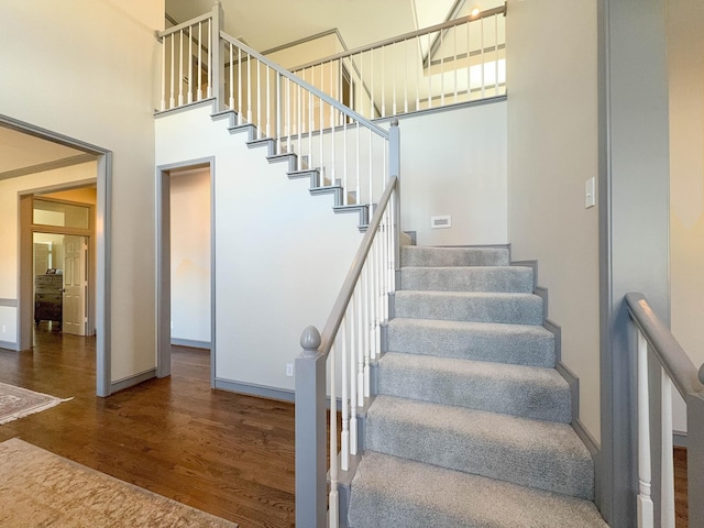 stairs with wood-type flooring and a high ceiling