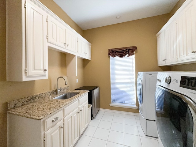 laundry area with cabinets, light tile patterned floors, sink, and washing machine and clothes dryer