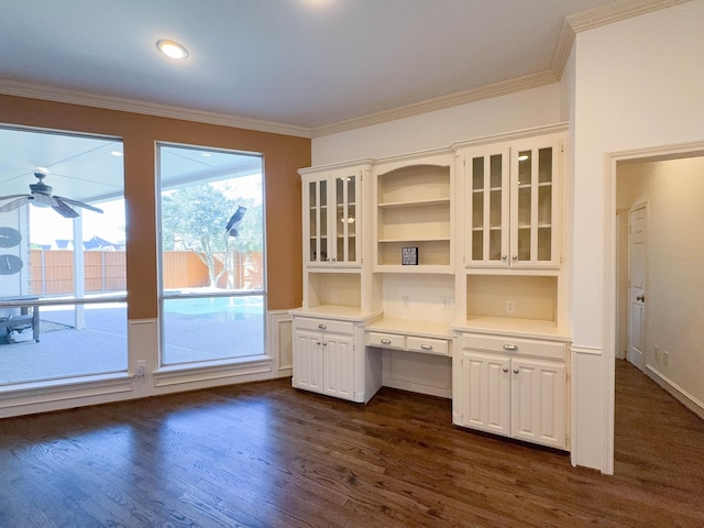 interior space with ornamental molding, dark hardwood / wood-style floors, built in desk, and ceiling fan