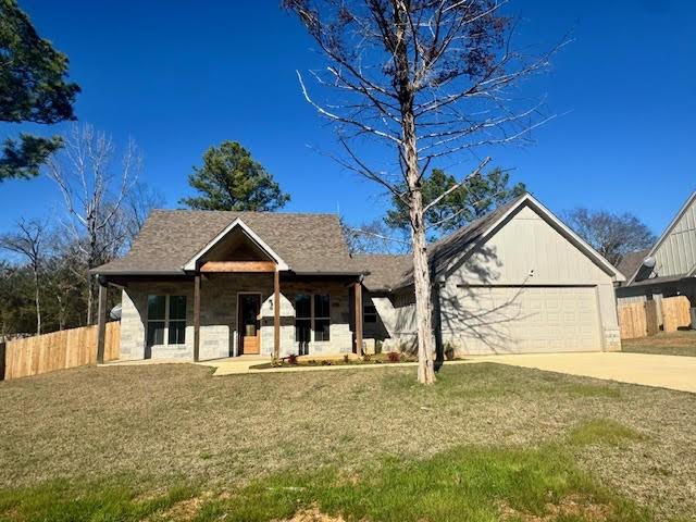 view of front of house featuring a front yard, a garage, and covered porch