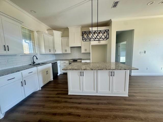 kitchen with white cabinetry, sink, a kitchen island, and decorative light fixtures