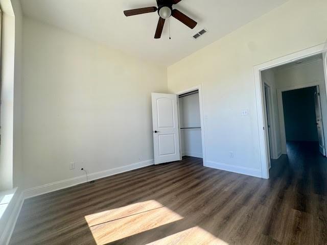 unfurnished bedroom with ceiling fan, dark hardwood / wood-style floors, and a closet