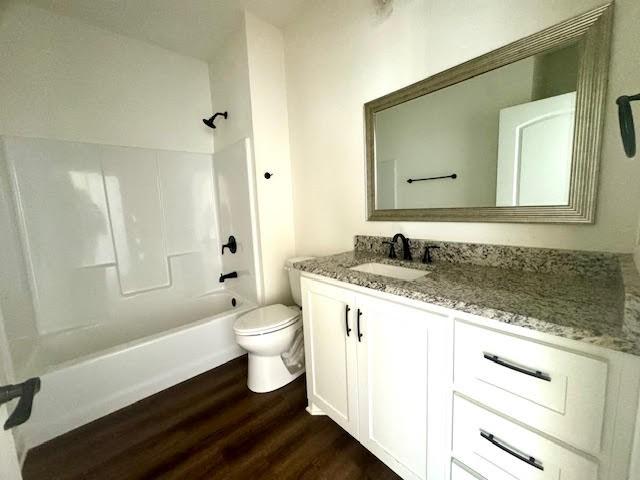 full bathroom with hardwood / wood-style flooring, vanity, shower / bathtub combination, and toilet