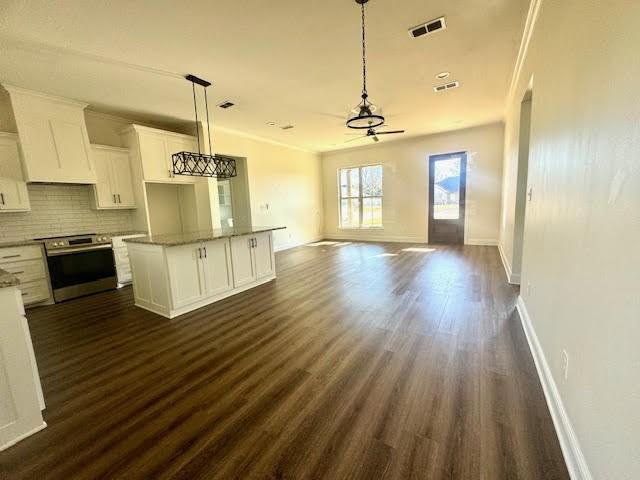 kitchen with tasteful backsplash, stainless steel range with electric stovetop, decorative light fixtures, white cabinets, and a kitchen island