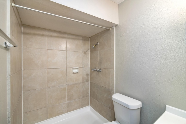 bathroom with a tile shower and toilet