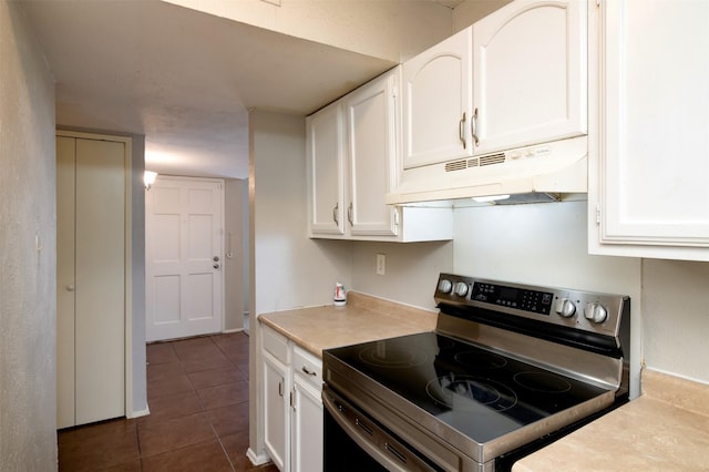 kitchen featuring dark tile patterned flooring, stainless steel electric range, and white cabinetry