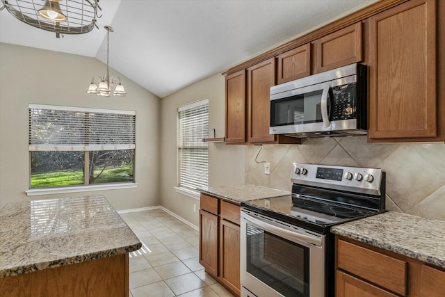 kitchen with vaulted ceiling, light stone countertops, light tile patterned floors, stainless steel appliances, and a chandelier