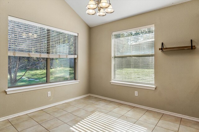 tiled spare room with a chandelier, a healthy amount of sunlight, and lofted ceiling