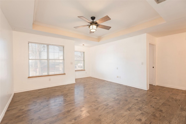 spare room with ornamental molding, dark wood-type flooring, and a tray ceiling