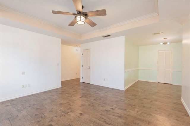 empty room with wood-type flooring, ceiling fan, crown molding, and a tray ceiling