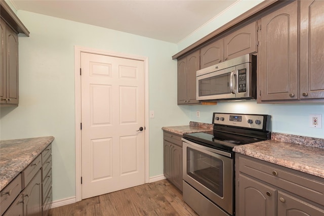 kitchen with appliances with stainless steel finishes and light hardwood / wood-style flooring