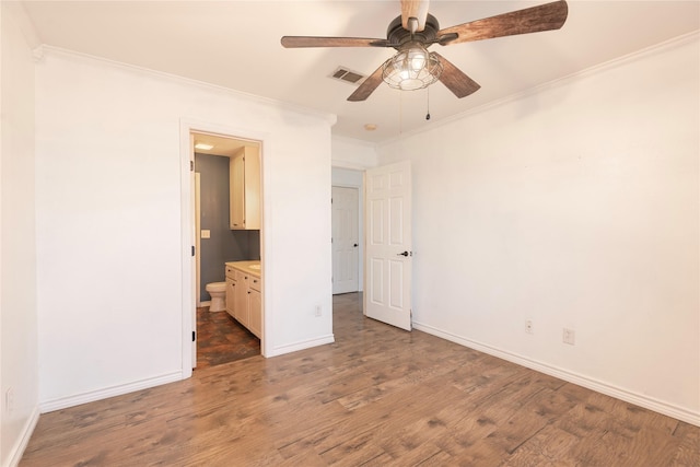 unfurnished bedroom with ornamental molding, dark wood-type flooring, connected bathroom, and ceiling fan