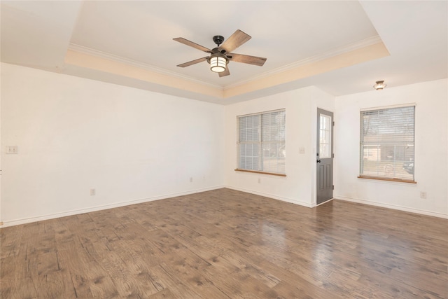 empty room featuring a tray ceiling, ornamental molding, dark hardwood / wood-style floors, and ceiling fan