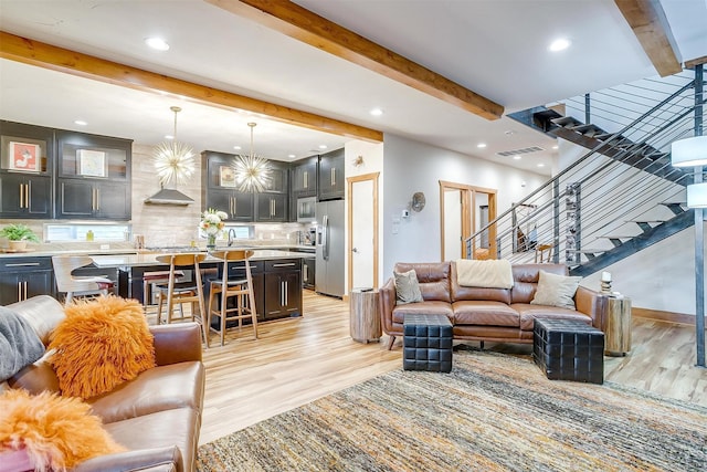 living room with sink, beamed ceiling, and light wood-type flooring